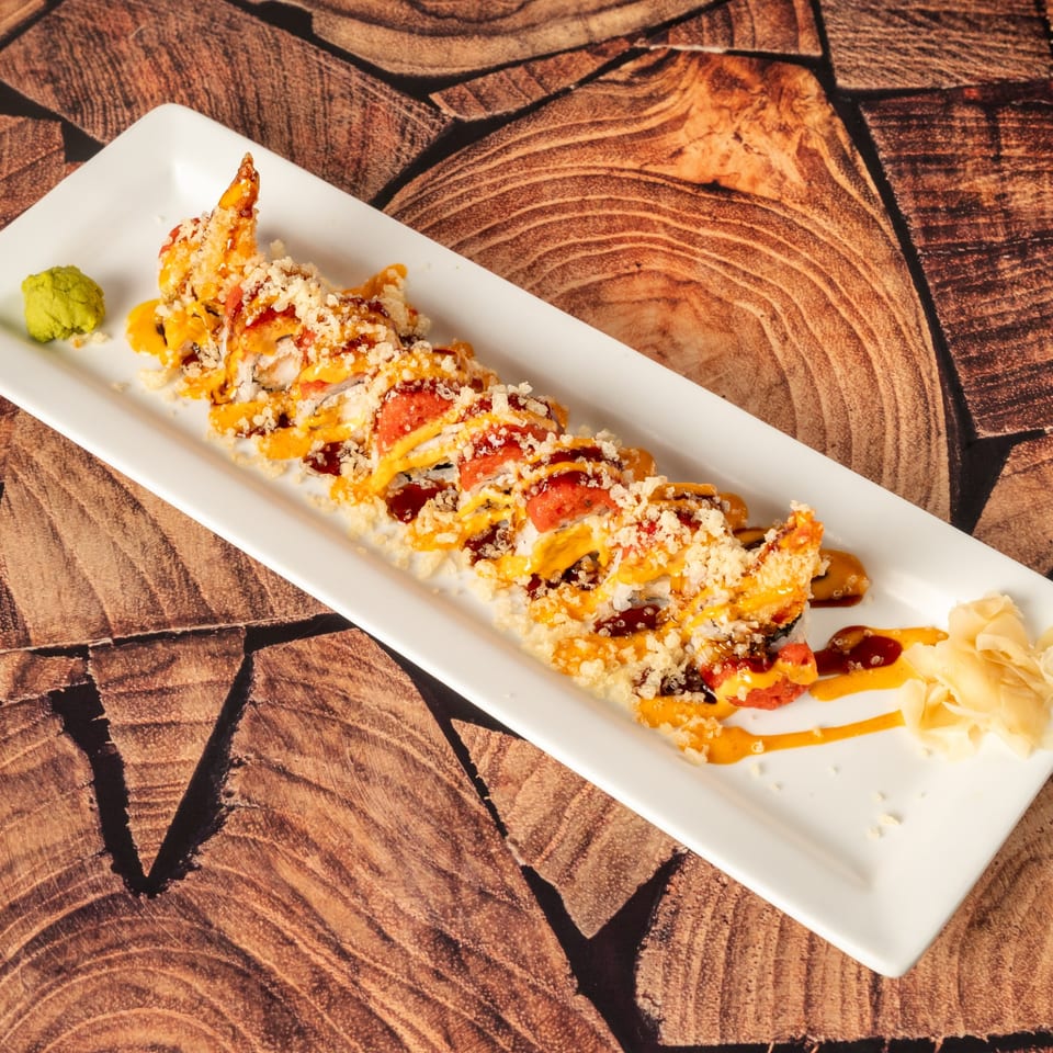 Kenji Sushi's fried shrimp tempura roll, drizzled with spicy mayo and eel sauce, served with wasabi and ginger.